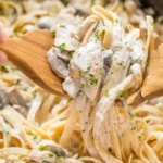 Creamy chicken fettuccine alfredo with tender pasta, sliced chicken, mushrooms, and parmesan sauce in a skillet.