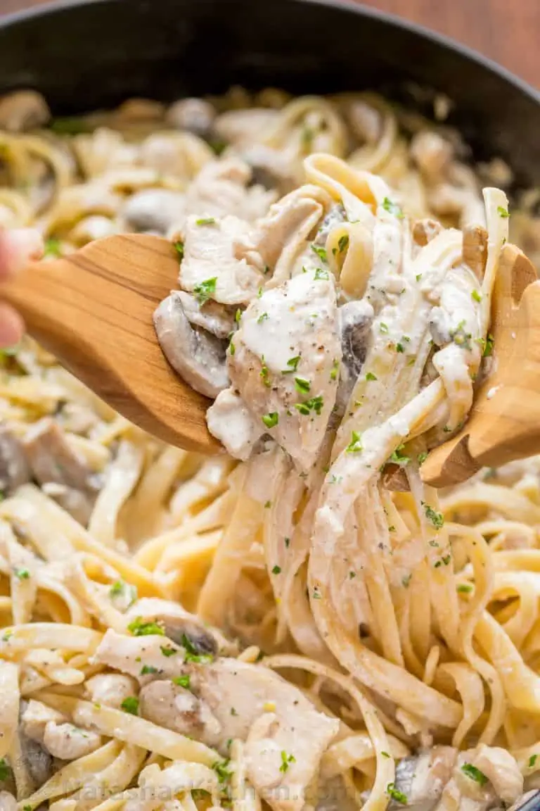Creamy chicken fettuccine alfredo with tender pasta, sliced chicken, mushrooms, and parmesan sauce in a skillet.