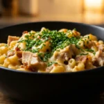 Creamy Chicken Mac and Cheese Recipe for Quick Family Dinners 7 Chicken Mac and Cheese in a black bowl with creamy cheese sauce, tender chicken pieces, elbow macaroni, and fresh chopped chives on top