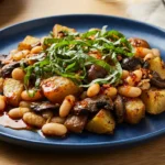 Delicious Mushroom and Kale Cannellini Bean Skillet 7 Mushroom and Kale Cannellini Bean Skillet on blue plate with golden roasted potatoes, white beans, sautéed mushrooms, and fresh basil ribbons on wooden table