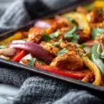 Sheet pan chicken fajitas with sliced chicken, bell peppers, and onions roasted together on a baking sheet