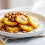 Fried plantains served with creamy blended beans and garnish on a plate