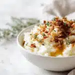 Creamy parsnip mash topped with brown butter crispy shallots, served warm in a bowl with golden garnish.