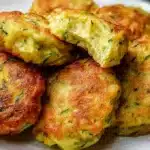 Zucchini fritters golden brown and crispy on a plate with dipping sauce