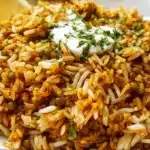 Lentils and rice served in a bowl with spices and herbs on top.